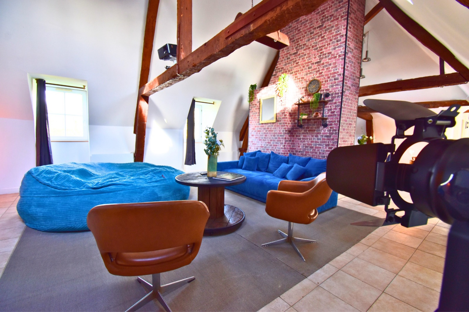 Le Loft des Charpentiers du Roi — salon avec canapé bleu sous charpente apparente